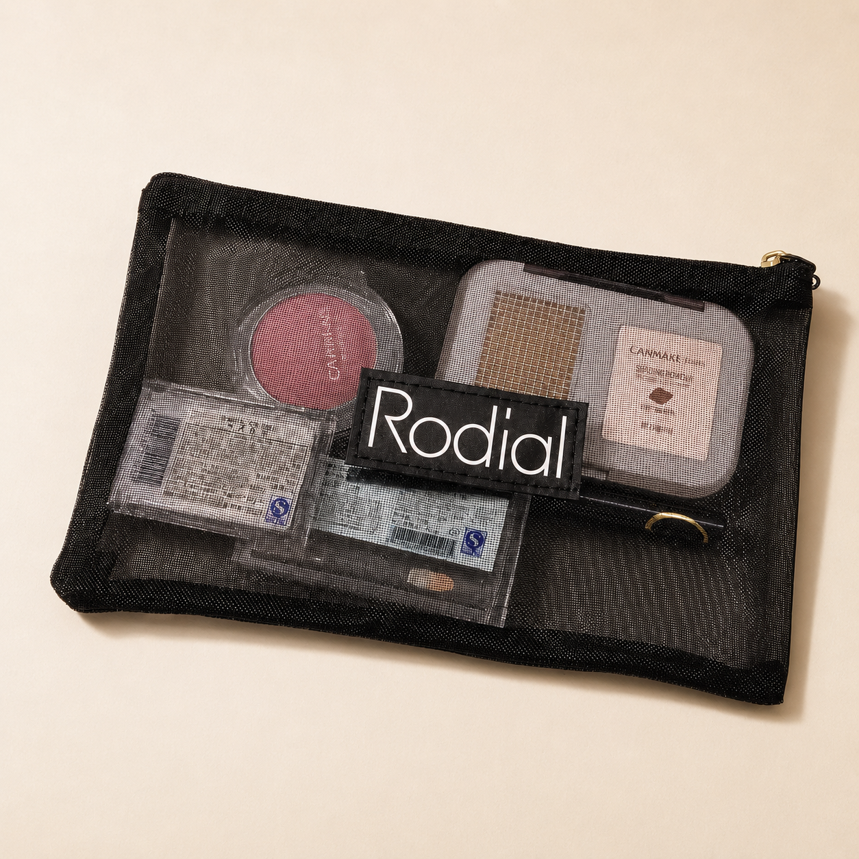 Black RODIAL mesh cosmetic bag showing beauty products through the see-through material